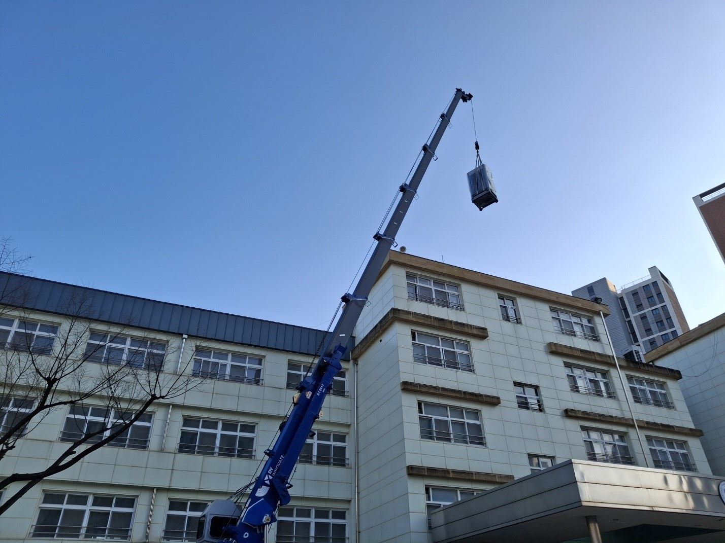 크레인으로 실외기를 학교 옥상으로 올리는 모습